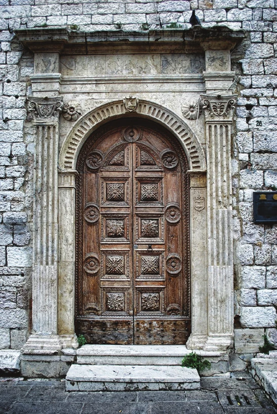 An arched carved wooden door in a stone doorway